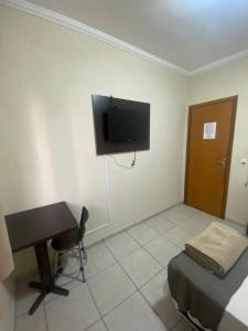 a room with a desk and a television on the wall at Dom Hotel in Maringá