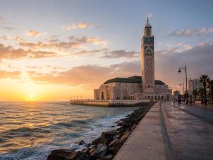 a building with a clock tower next to the ocean at Maison traditionnelle cadablabca centre in Casablanca