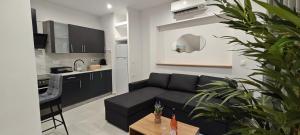 a living room with a black couch and a kitchen at Alexandras Maisonette in Skiathos
