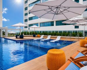 a swimming pool with lounge chairs and umbrellas at Flat 503 - America in Campos dos Goytacazes