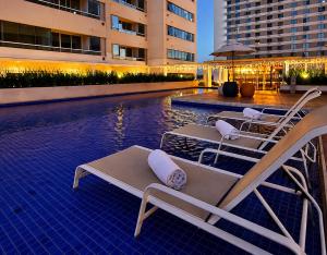 a group of lounge chairs sitting next to a swimming pool at Flat 503 - America in Campos dos Goytacazes