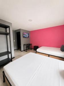 ein Zimmer mit zwei Betten und einer rosa Wand in der Unterkunft Adhoc Macro in Monterrey