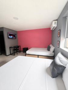 ein Schlafzimmer mit zwei Betten und einer roten Wand in der Unterkunft Adhoc Macro in Monterrey + 4 Fotos