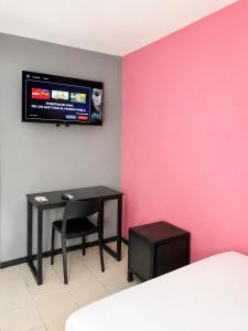 Ein Zimmer mit einem Tisch und einem Fernseher an einer rosa Wand in der Unterkunft Adhoc Macro in Monterrey