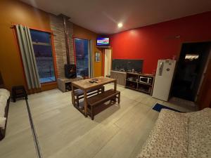 a living room with a table and a refrigerator at La Alea Malalcahuello in Malalcahuello