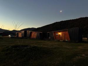 a row of wooden huts in a field at sunset at La Alea Malalcahuello in Malalcahuello