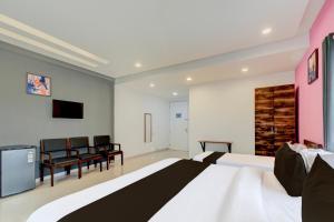 a bedroom with a bed and chairs and a tv at Super Hotel O SRI NIRVANA PLAZA in Gachibowli