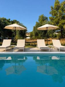 a group of chairs and umbrellas next to a swimming pool at Minimal Suites in Skala Rachoniou