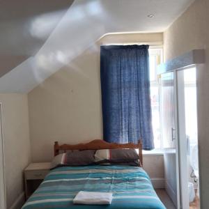 a bedroom with a bed with a blue curtain and a window at New Hawkes Hotel in Blackpool