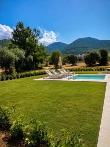 a garden with a swimming pool and a lawn at Minimal Suites in Skala Rachoniou