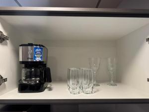 a shelf with glasses and a coffee maker on it at Studio UNI 15 - Unipar, Lago e Shopping in Toledo +11 photos