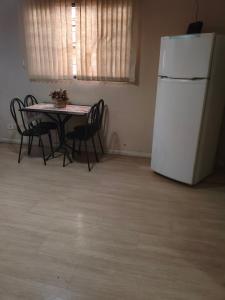 a kitchen with a table with chairs and a white refrigerator at Hostel Durães 01 in Londrina