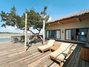 a wooden deck with two chairs and a house at Kiterise Tatajuba in Tatajuba