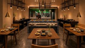 a restaurant with tables and a chef in the background at Ureshino Onsen Yusyuku Sarayama in Ureshino