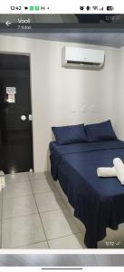 a bedroom with a blue bed and a black door at suítes Arco-íris in Uberlândia