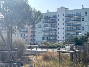 a building with a tree in front of a fence at Studio face mer L'escapade marine in Calais