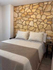 a bedroom with a stone wall with a bed at Los Ayales in Huelamos