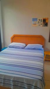 a bed with a blue and white striped comforter at Recanto Dos Vargas - Seu refúgio em Floripa com atendimento dos anfitriões in Florianópolis