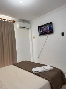 a bedroom with a bed with a tv on the wall at Araújo Hotel in Itaberaba