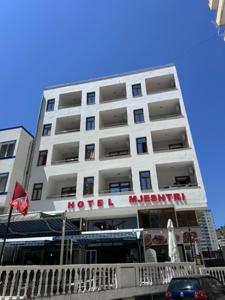 a large white building with a sign on it at Hotel Mjeshtri in Shëngjin
