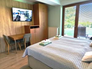 a bedroom with a bed and a table and a television at Apartmány Kvetná in Rajecké Teplice