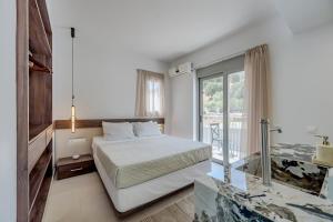 a white bedroom with a bed and a balcony at Evgoro Luxury Suites in Agia Galini +66 photos