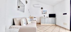 a white living room with a couch and a tv at Casa Minuredda in Olbia