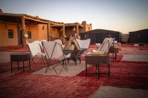 a group of chairs and tables on a rug at Sahara Sunset Luxury Camp M'hamid in Mhamid +39 photos