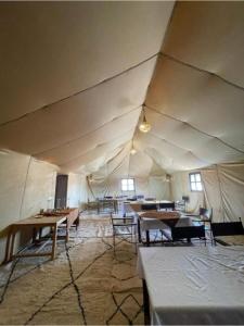 a room with tables and chairs in a tent at Sahara Sunset Luxury Camp M'hamid in Mhamid