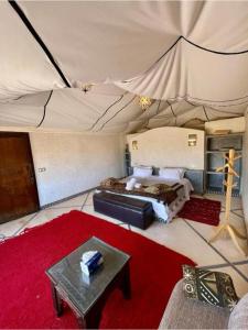 a bedroom with a tent with a bed and a table at Sahara Sunset Luxury Camp M'hamid in Mhamid
