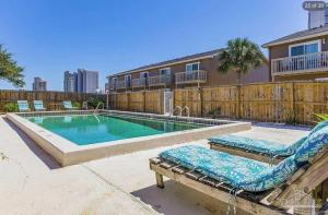 a swimming pool with two lounge chairs next to a house at Spacious Condo with full kitchen shared pool and beach access in Perdido Key