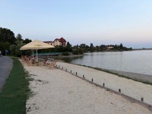 a beach with chairs and an umbrella next to the water at Karavan u přehrady in Prostějov +3 photos