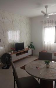 a living room with a table and a television at Apt a 500m da praia do forte in Cabo Frio