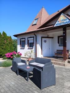 a patio with chairs and a table in front of a building at Holiday Apartman in Bük