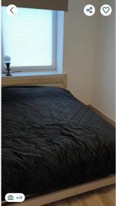 a bed in a room with a window with a black blanket at Polna 16 in Mrągowo