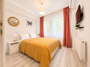 a bedroom with a bed with a yellow blanket and a window at Askin Suits Canakkale in Çanakkale