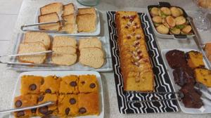 a table topped with different types of bread and desserts at Dom Hotel in Maringá