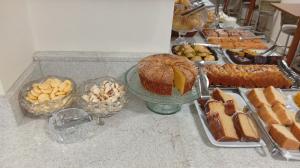 a counter topped with different types of bread and desserts at Dom Hotel in Maringá