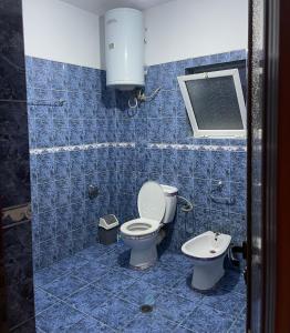 a blue tiled bathroom with a toilet and a sink at Family-friendly in Pogradec +18 photos