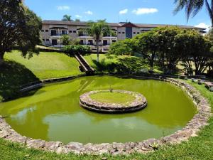 a pond filled with green water in front of a building at Serra Negra Piemonte Flat Paz e Lazer Num Só Lugar in Serra Negra