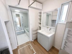 a white bathroom with a sink and a mirror at Akatsuki Villa 暁 in Asahikawa