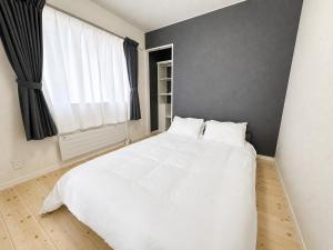 a bedroom with a white bed and a window at Akatsuki Villa 暁 in Asahikawa