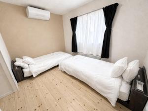 a bedroom with two beds and a window at Akatsuki Villa 暁 in Asahikawa