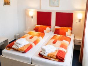 two beds in a bedroom with red and orange blankets at Hotel & Restaurant Möwchen in Norden