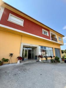 a red and yellow building with flowers in front of it at Casa Romai Portas in Romay