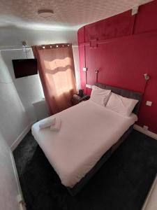 a bedroom with a large white bed with red walls at Harbour Stays in Skegness