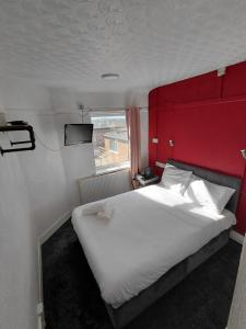 a bedroom with a large white bed with a red headboard at Harbour Stays in Skegness