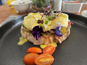 a sandwich on a black plate with vegetables on it at Africa Prestige Boutique Hotel in Benoni