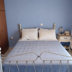 a blue bedroom with a metal bed with white pillows at mastic flavored sweet in Chios