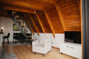 a living room with a white chair and a television at Apartamenty Labuda in Garcz